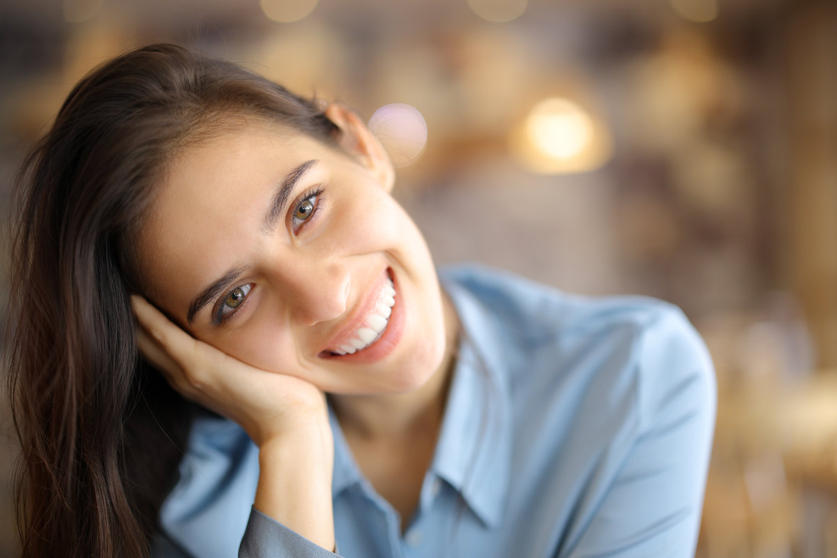 Portrait of a happy woman looking at you in a bar interior