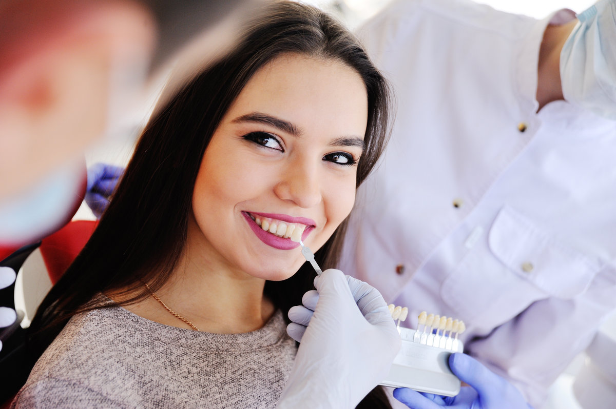 The dentist selects a shade of tooth enamel using a special scale of the table